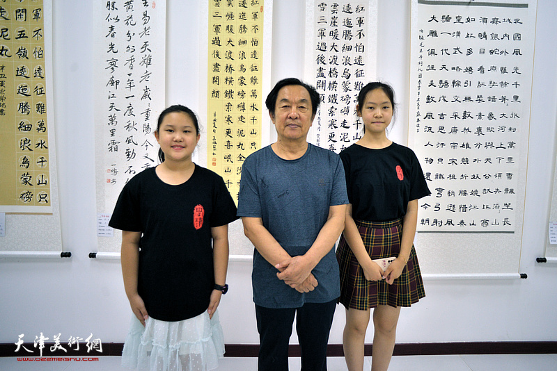 王全聚与优秀学员代表王涵艺、张露影在“师生同书毛主席诗词展”现场。