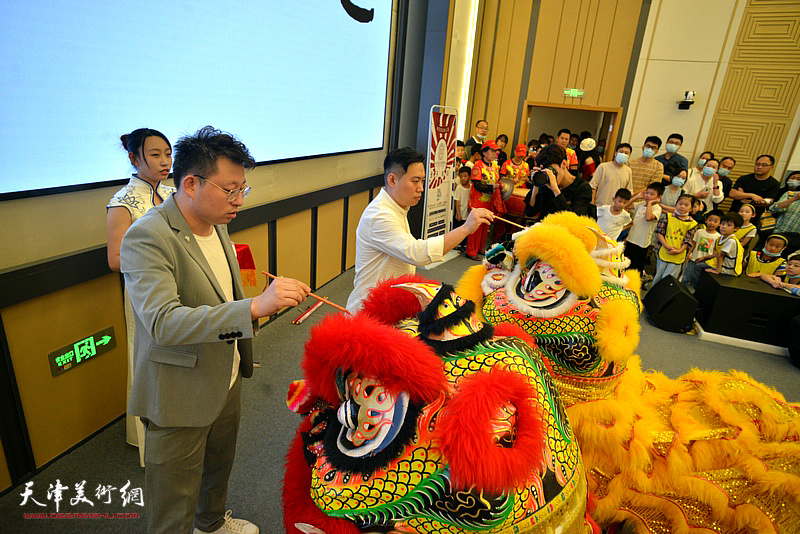 许琨、王允在主题书画展现场为舞狮点睛，寄托避除瘟疫，吉祥