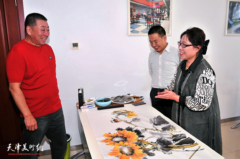 邱成国、李洪彬观赏崔燕萍书画创作。