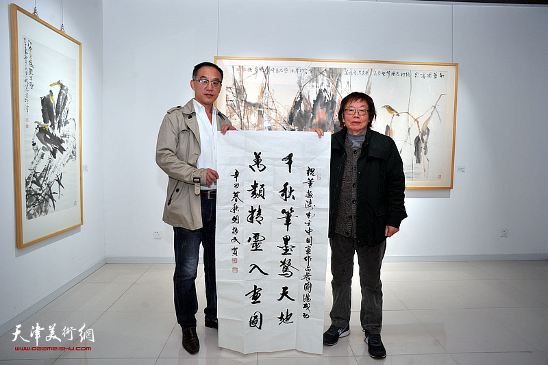 董振涛在画展现场展示胡振民为画展题写贺词：千秋笔墨惊天地，万类精灵入画图。。