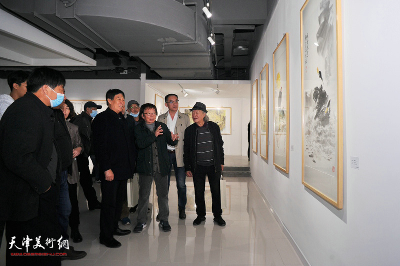 董振涛与来宾在画展现场观赏画作。