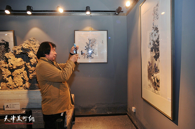 史振岭观赏展出的菊花题材书画作品。
