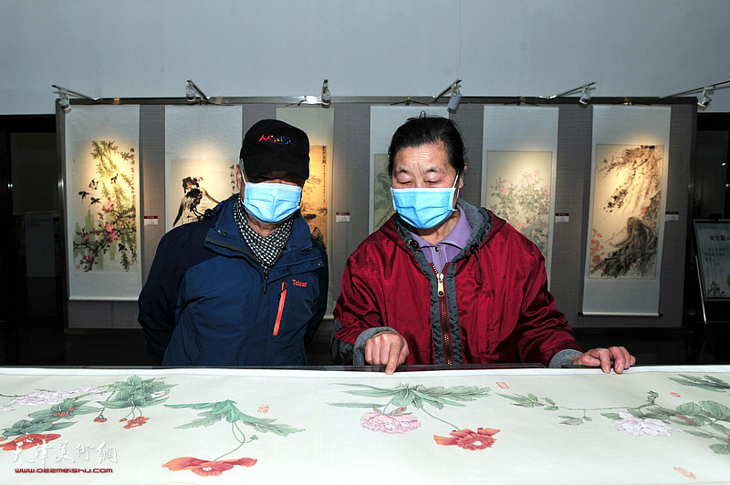 张明荣陪同嘉宾观赏展出的作品。