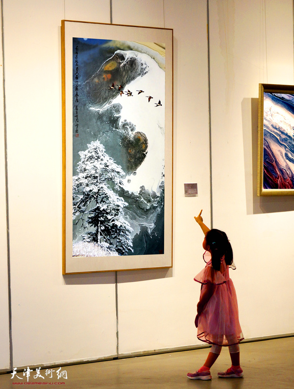 一位喜欢画画的小朋友在展览现场仔细观看霍然先生的泼彩作品。