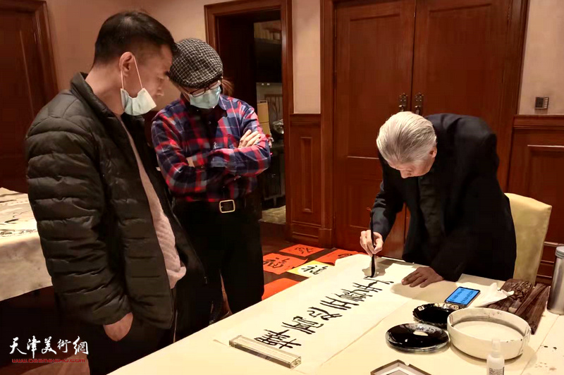 天津巨龙画院恭贺新春，图为杨德树先生现场写书法。
