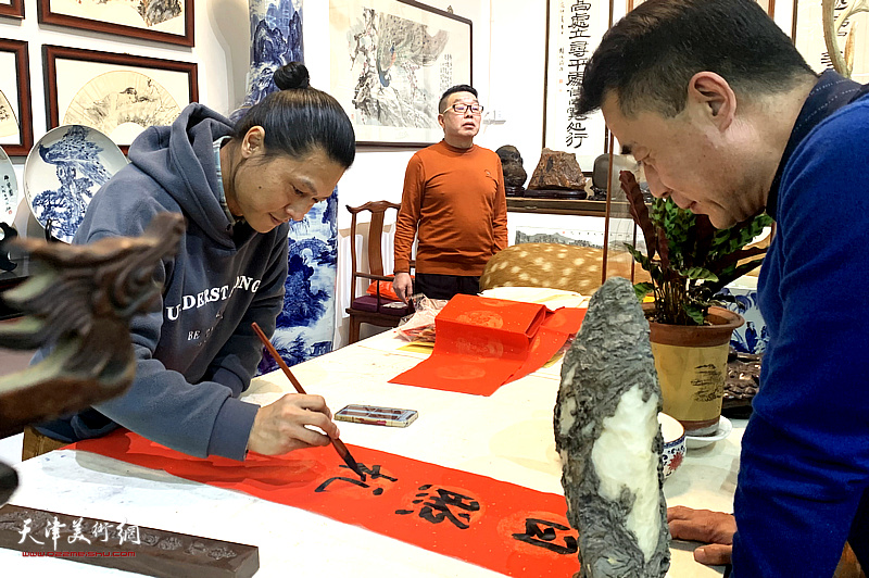 天津巨龙画院恭贺新春，图为姚铸先生现场写福字。