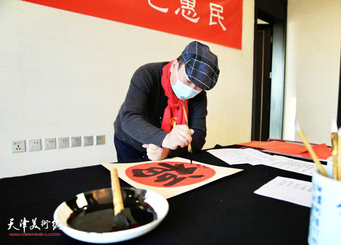天津市美协理事范权在活动中写福字。