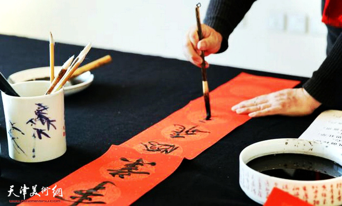 天津市美协理事范权在活动中写春联。