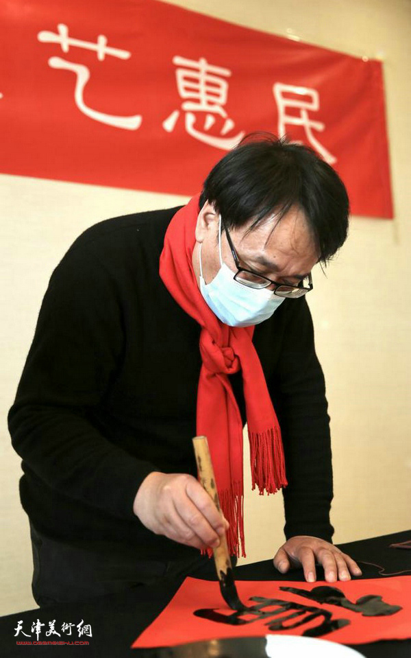 天津画院专职画家张晓彦在活动中写福字。