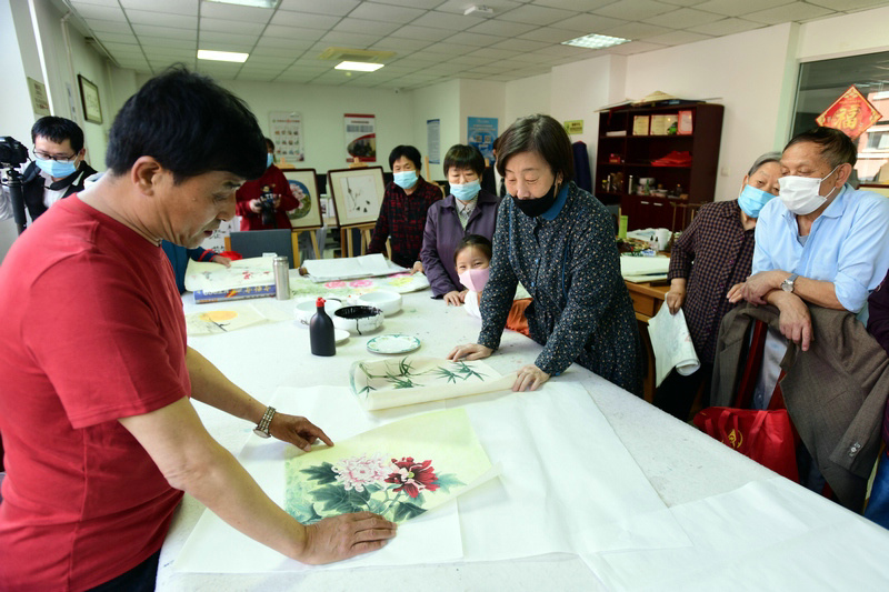 著名花鸟画家王群英在航天城社区为书画爱好者辅导作品。