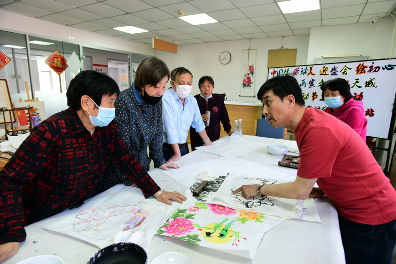 著名花鸟画家王群英在航天城社区为书画爱好者辅导作品。