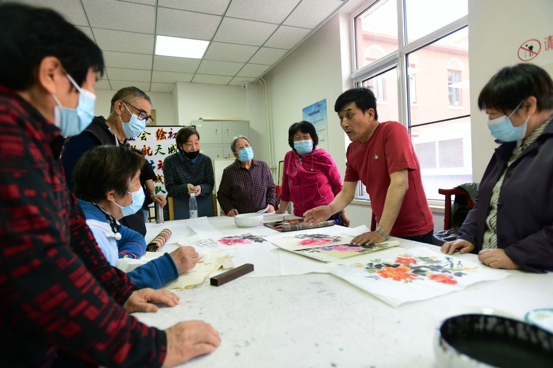 著名花鸟画家王群英在航天城社区为书画爱好者辅导作品。