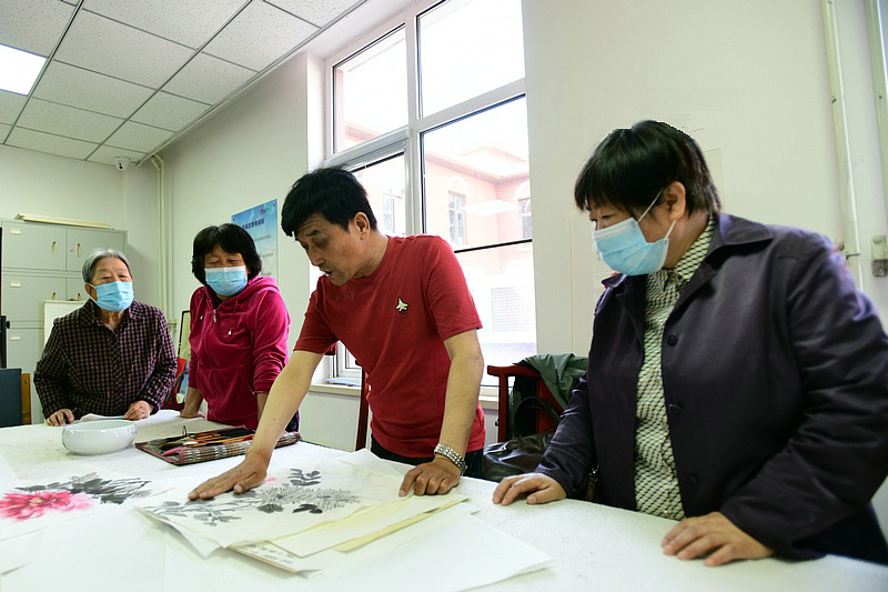 著名花鸟画家王群英在航天城社区为书画爱好者辅导作品。