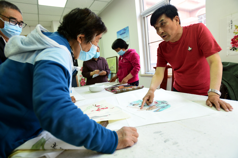 著名花鸟画家王群英在航天城社区为书画爱好者辅导作品。