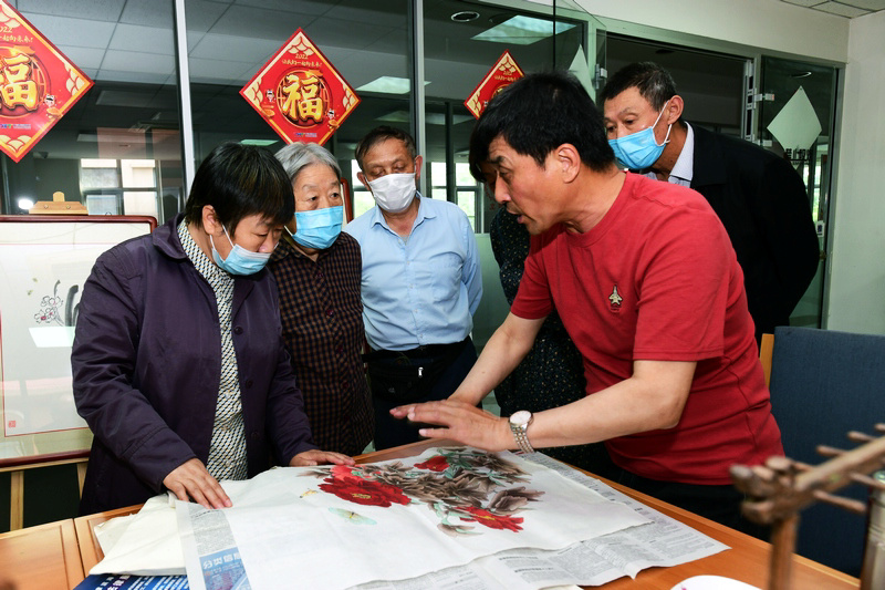 著名花鸟画家王群英在航天城社区为书画爱好者辅导作品。