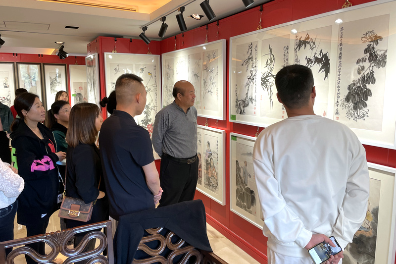 孟庆占与书画爱好者在画展现场观赏画作。