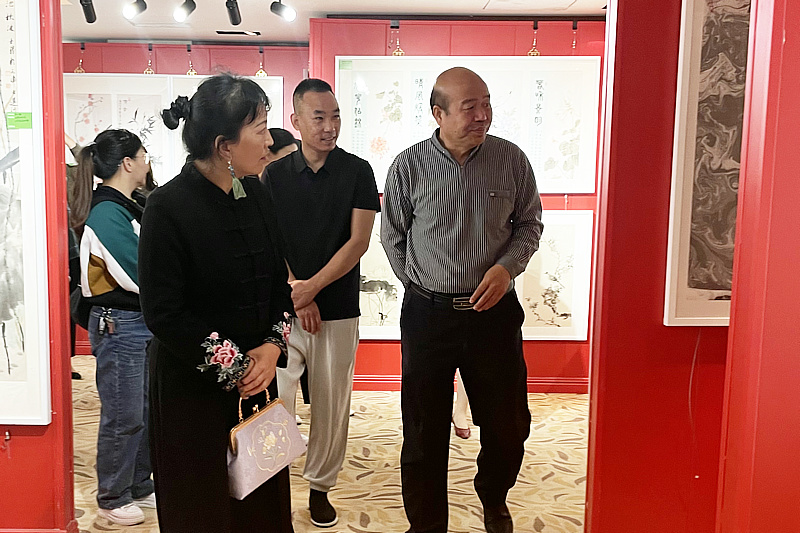 孟庆占与书画爱好者在画展现场观赏画作。