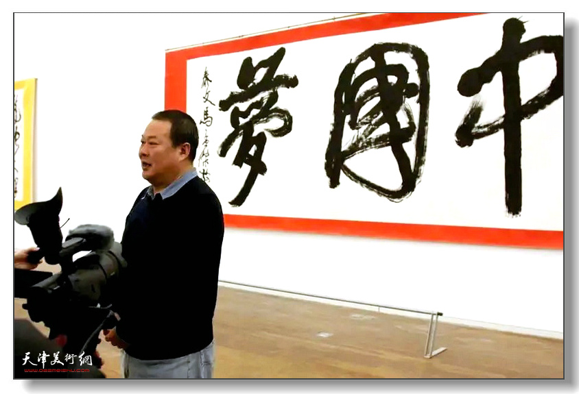 马孟杰在自己创作的“中国梦”书法前接受采访
