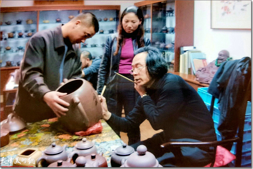 霍春阳先生在宜兴为叶永君画紫砂巨型壶；旁边为叶永君夫妇。（2005年）