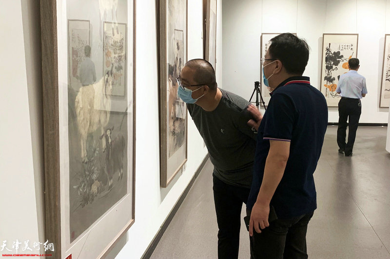 张晓彦、颜萌观赏展出的画作。