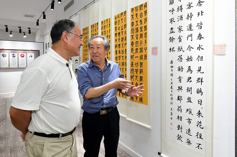 刘国胜、张智龙观赏展出的作品。