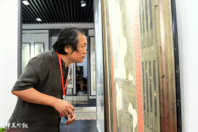 杨惠东观赏展出的画作。