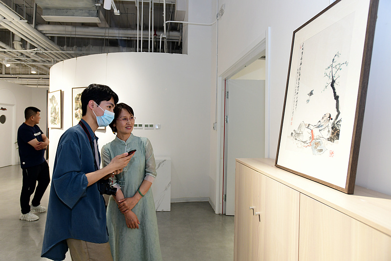 来宾在画展现场观赏展出的作品。