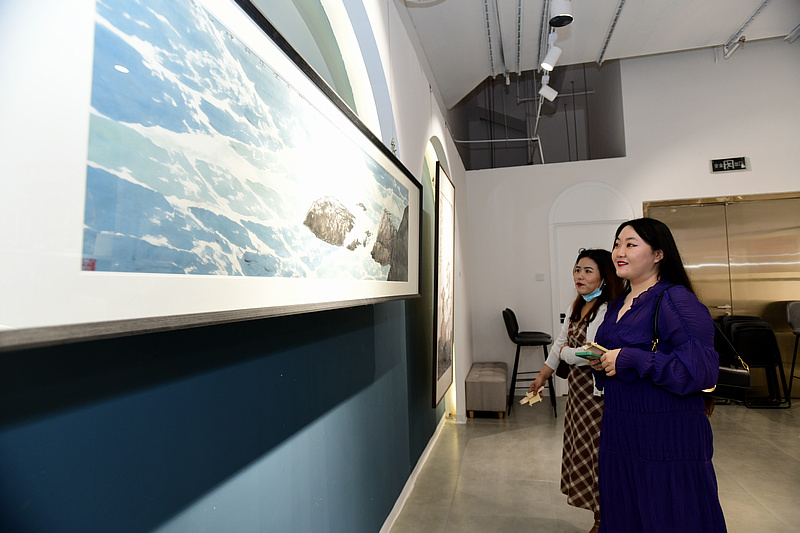 来宾在画展现场观赏展出的作品。