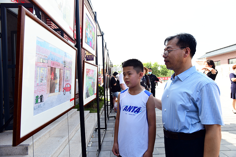 王宏志与小画家一起观赏展出的作品。