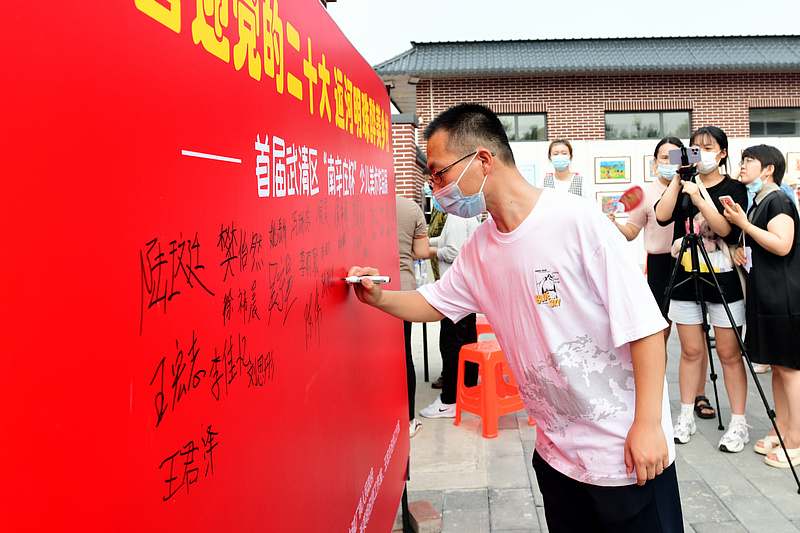 王梓珑在展览签到墙上签名。