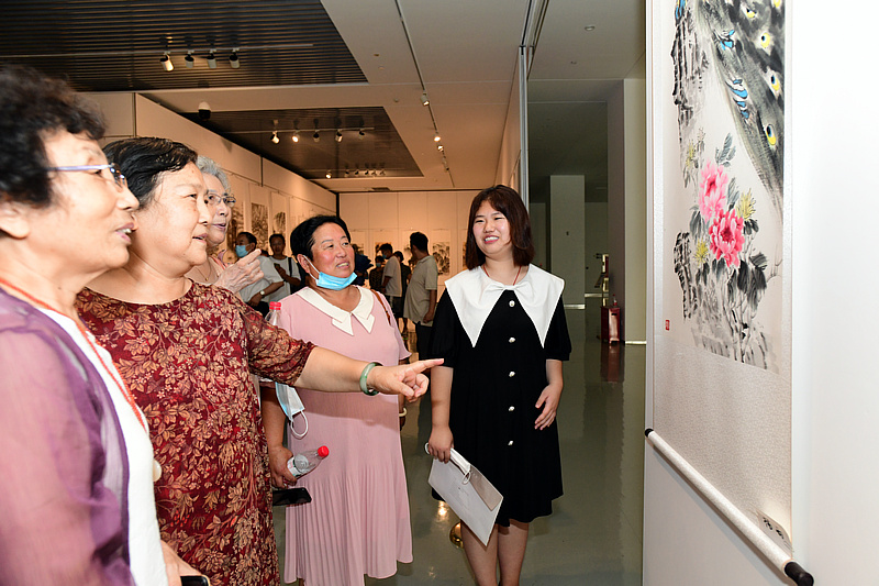 青年画家杨雨在画展现场介绍展出的作品。