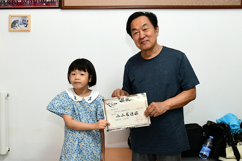 王全聚为蒋雨含小朋友颁发“小小书画家”证书。