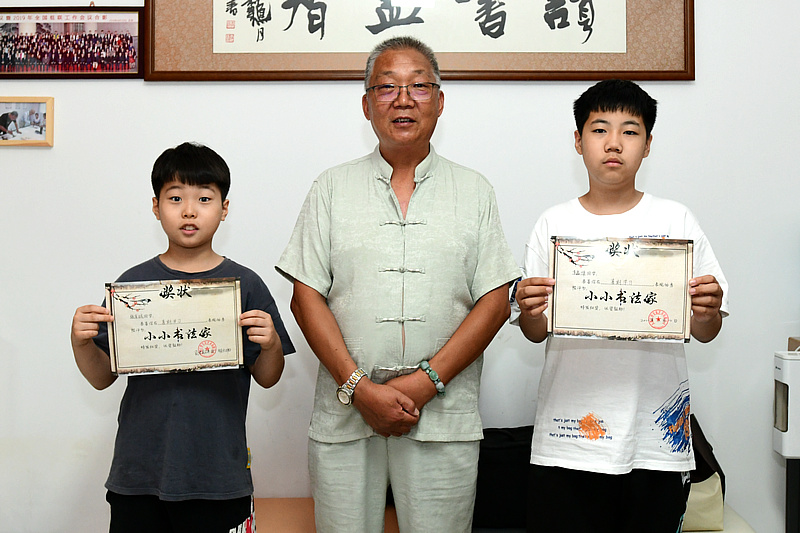 赵炳刚为张育诚、李鑫博小朋友颁发“小小书画家”证书。