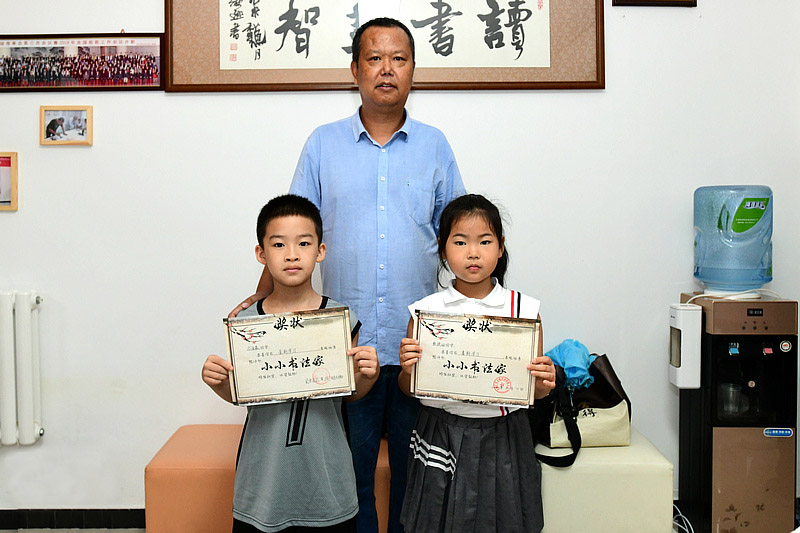 李建军为张语涵、刘金森小朋友颁发“小小书画家”证书。