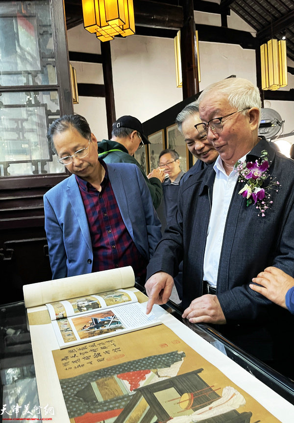 彭连熙在画展现场向嘉宾介绍展出的作品。