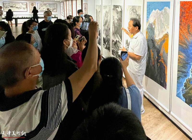 霍然老师在画展现场向观众介绍展品。