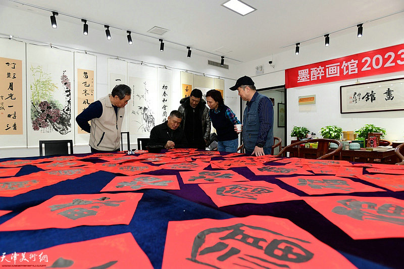天津墨醉画馆的书画家在展览现场写福字