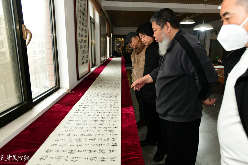 著名书画家张法东向张同明、杨文介绍展出的作品。