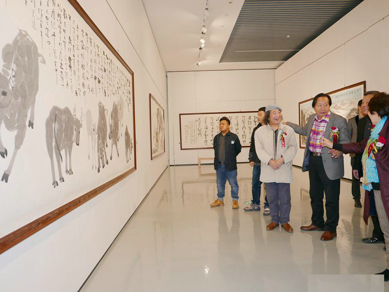 张明光先生（左三）在“百年辉煌”天津湖社美术家作品展现场参展作品前 